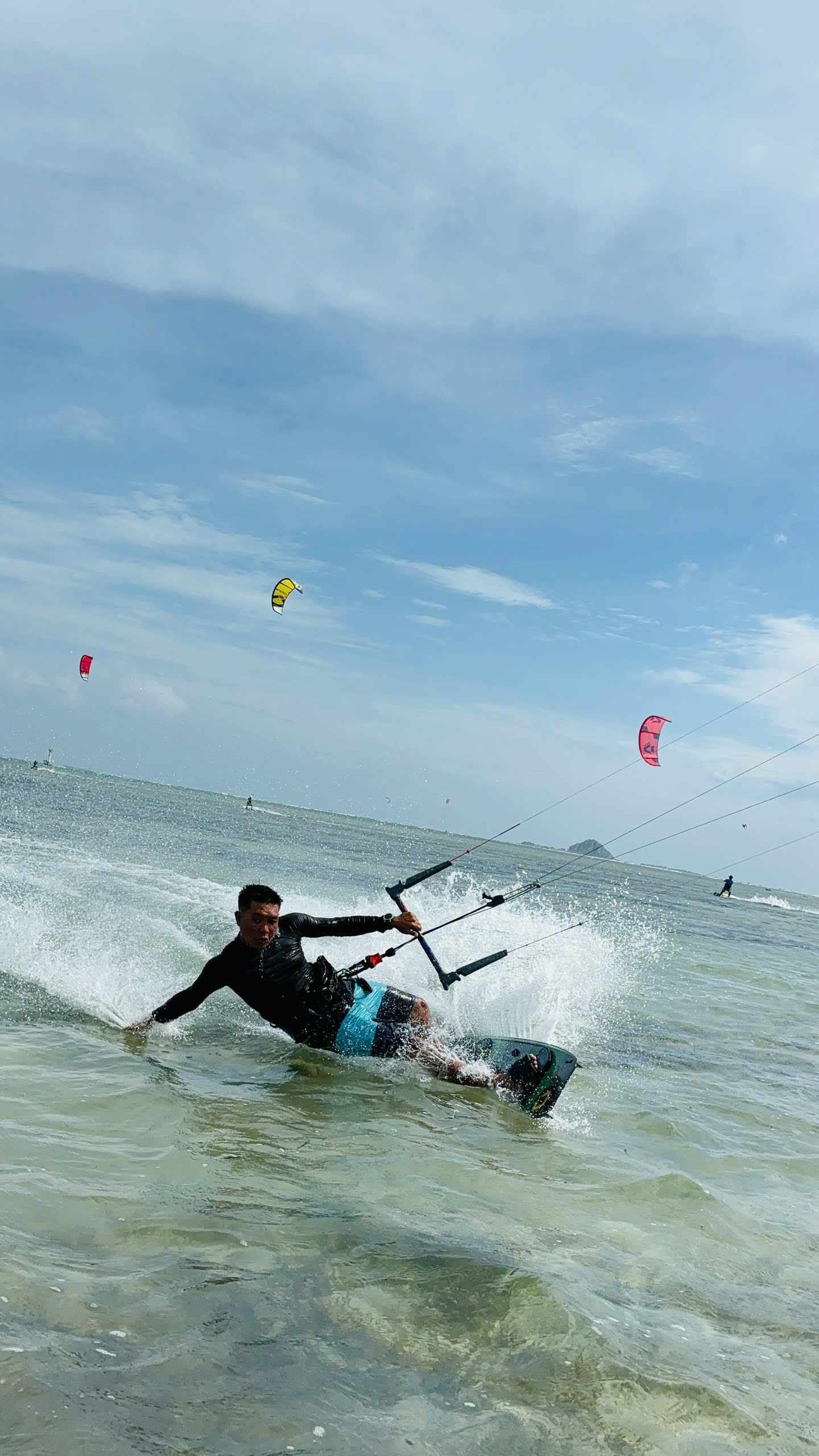 Kiteboarder riding across the water with kites in the sky